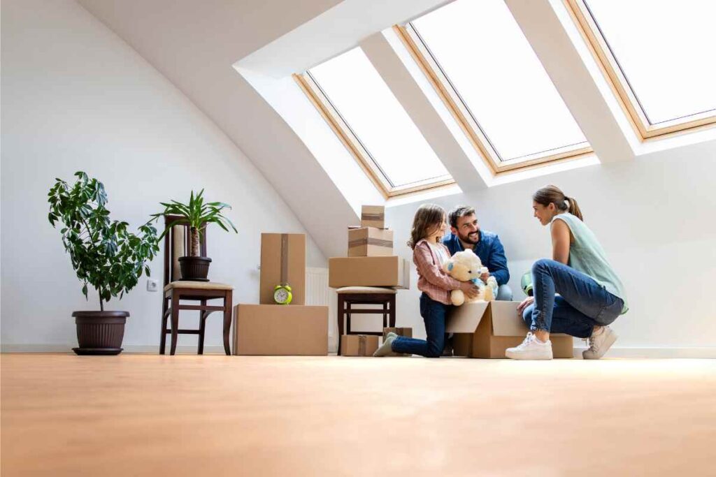 Family unpacking moving boxes together in a bright attic room